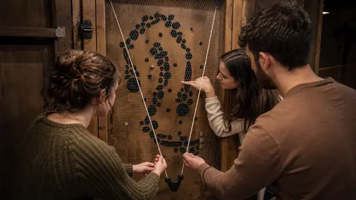Vier Personen entschlüsseln im Escape Room in Oberkirch ein Muster an einer Holztür mit gespannten Schnüren