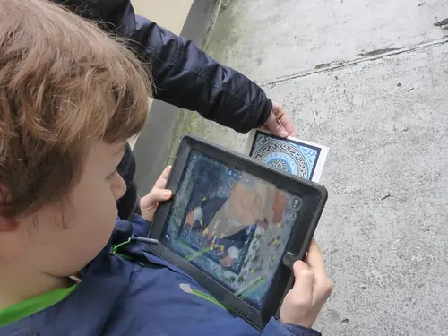 Kind hält beim Outdoor-Exitgame in Oberkirch ein Tablet und vergleicht es mit einer Hinweiskarte